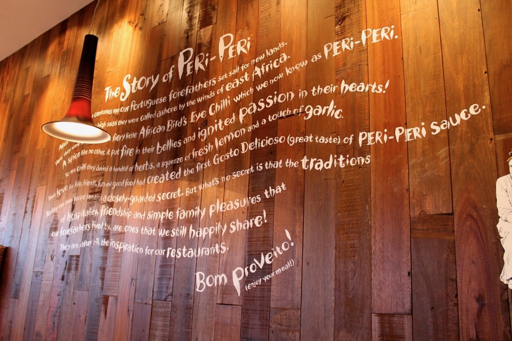 Hand-painted story lettering across a timber wall at Nandos